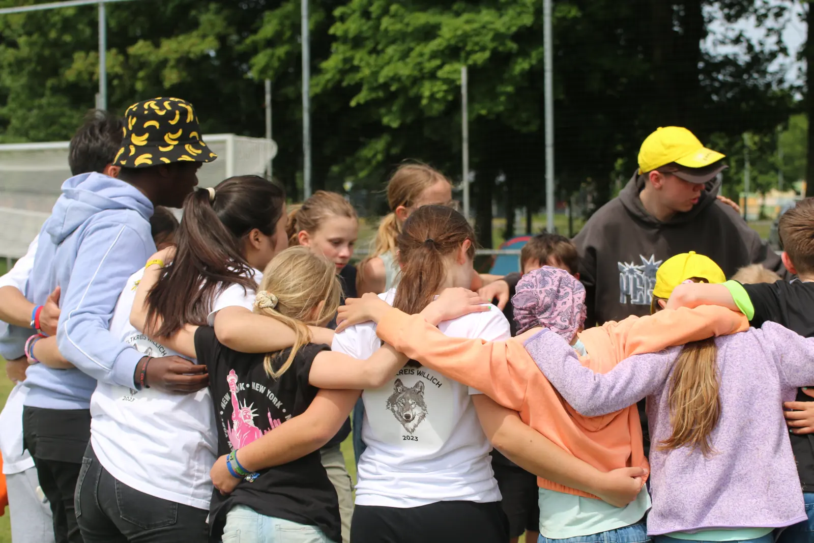 Kinder und Jugendliche stehen beim Pfingstzeltlager Arm in Arm im Kreis